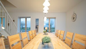 Un espace repas comprenant une table en bois, des chaises et un luminaire suspendu.