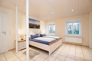 A bedroom with a bed, nightstands, a window, and a radiator. - Beacon - Nordseehof Fuhlehörn (Nordstrand)
