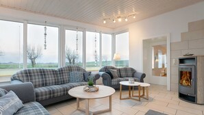 Un salon moderne comprenant un ensemble de canapés, une table basse ronde, une petite table et un poêle à bois.