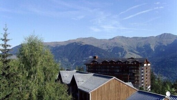 Un chalet de montagne avec une façade en bois et une vue sur les montagnes environnantes.