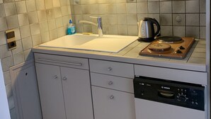 Une cuisine équipée d’un évier, d’un lave-vaisselle, d’une cuisinière et d’une horloge murale.