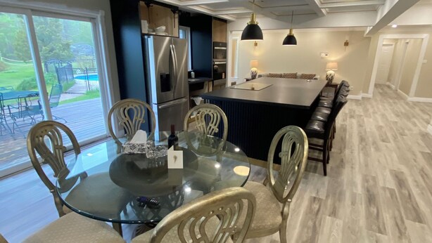 Una cocina moderna con una isla central, electrodomésticos de acero inoxidable y una zona de comedor con mesa de vidrio y sillas acolchadas.