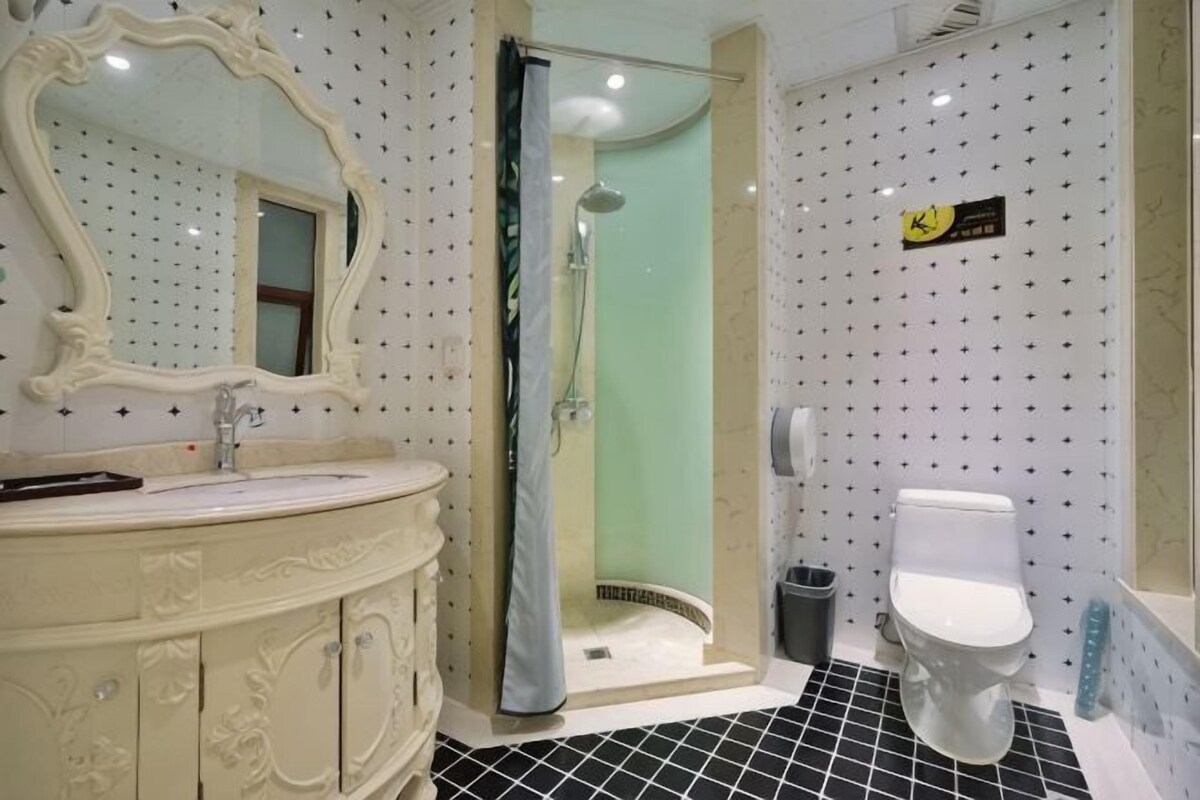 A bathroom with a white vanity, a shower, and a toilet.