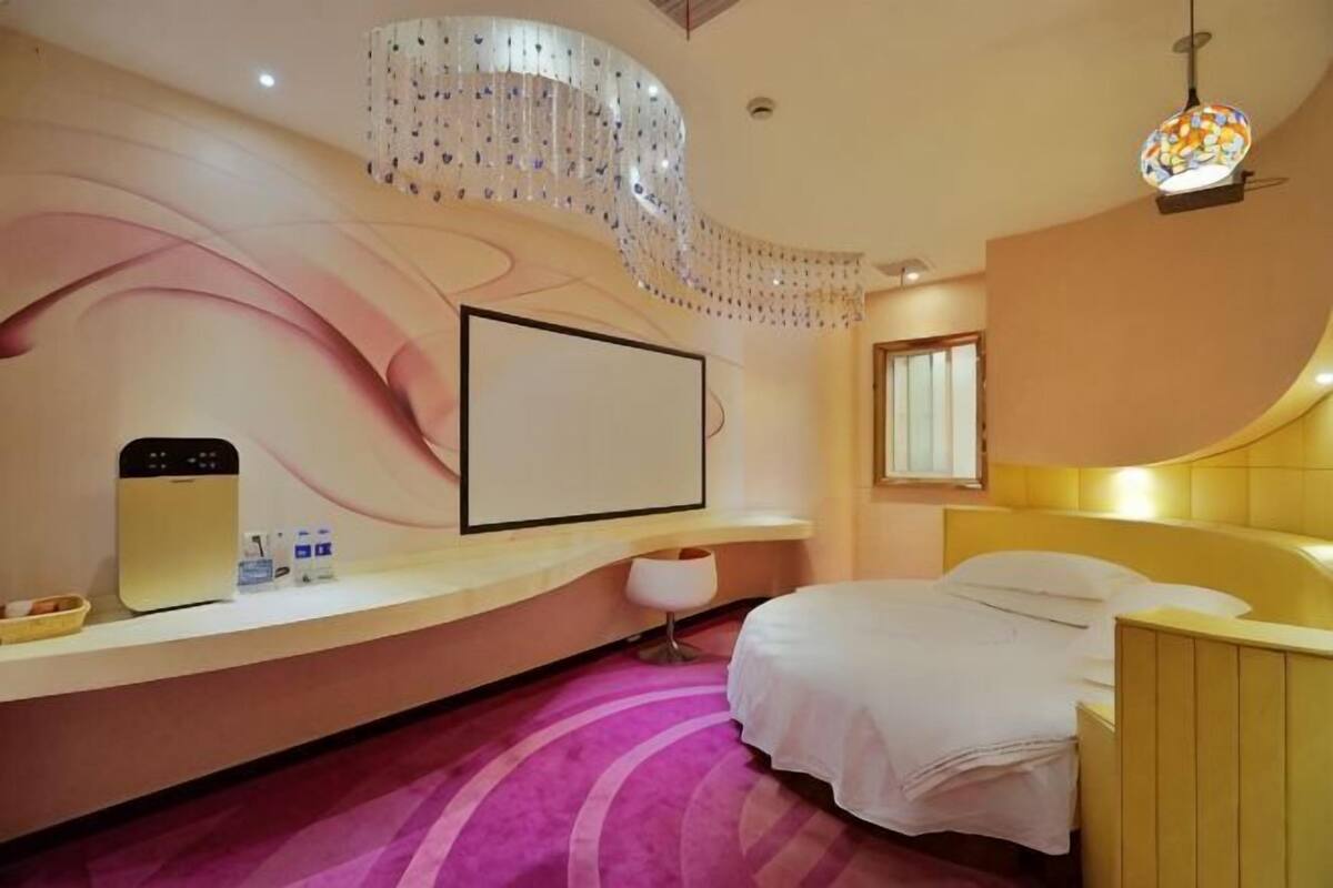 Une chambre d’hôtel moderne avec un mur incurvé, un lit, un bureau et une grande fenêtre.
