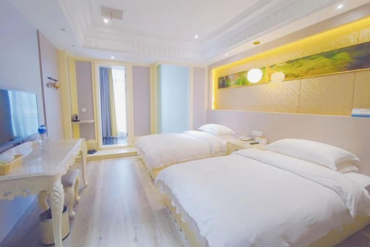 A hotel room with two beds, a desk, and a television.