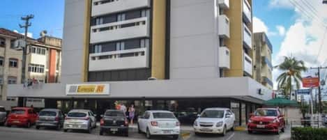 A multi-story building with a parking lot in front.