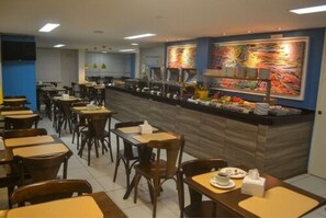 Um restaurante com balcão, mesas e cadeiras.