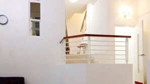 A staircase with a handrail, a small rug, and a sofa in a room with white walls and a tiled floor. - HomeStay Nimah Seaview (George Town)