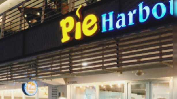 An outdoor seating area with tables and chairs, a sign reading "Pie Harbor," and a menu board outside the establishment. - HomeStay Nimah Seaview (George Town)