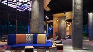 A modern lobby with a blue sofa, patterned cushions, and geometric lighting fixtures. - Aloft by Marriott Langkawi Pantai Tengah (Langkawi)