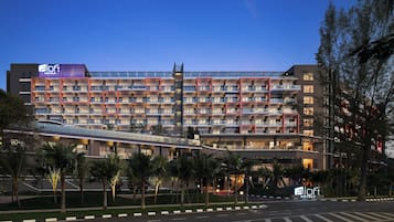 Ein modernes Hotel mit mehreren Etagen, einem überdachten Gang und einem gut beleuchteten Eingang.