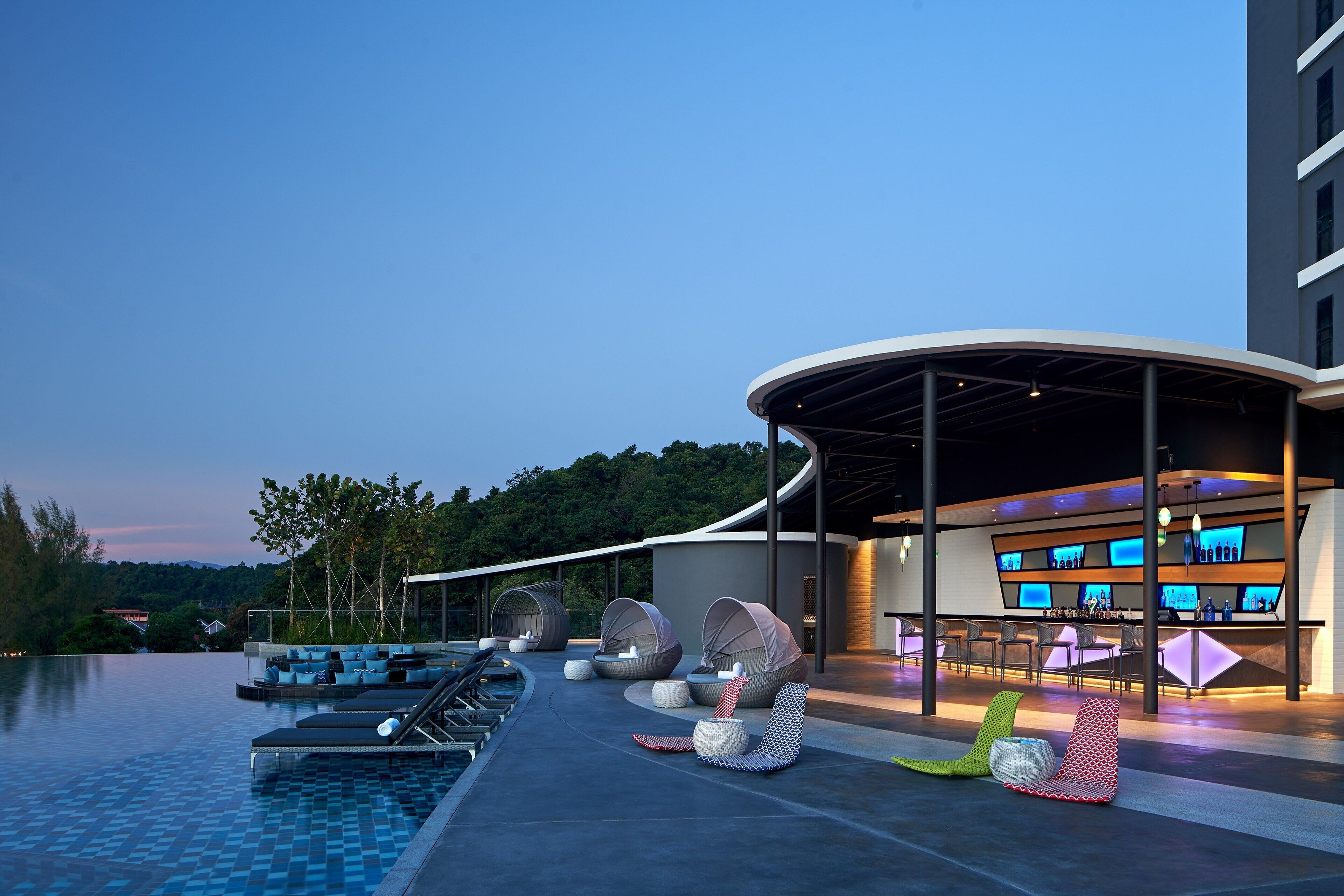 A modern outdoor pool area with lounge chairs and a bar.