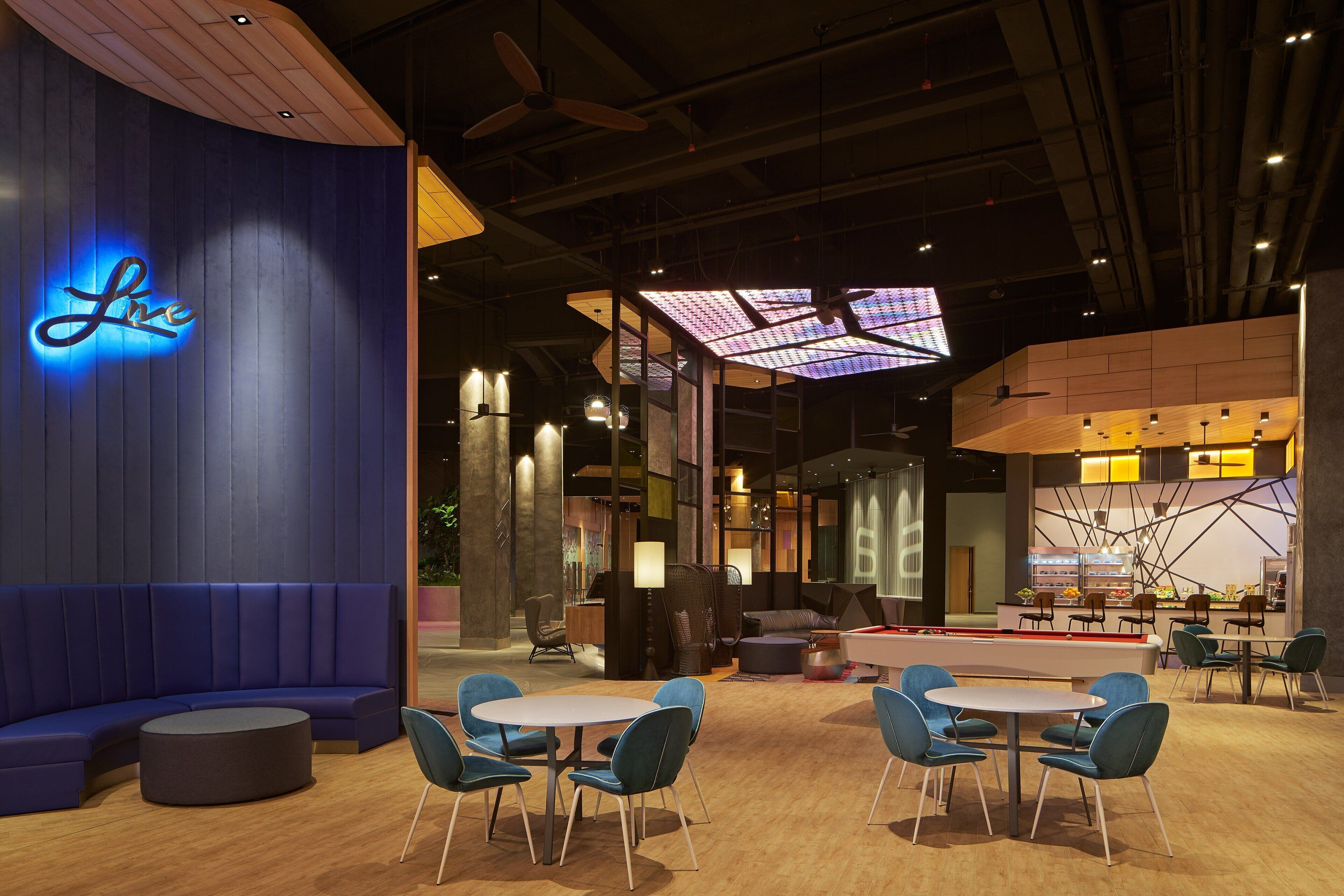 A modern lounge area with a curved blue seating area, round tables, and blue chairs.