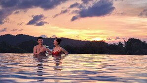Una pareja en una piscina con un atardecer de fondo.