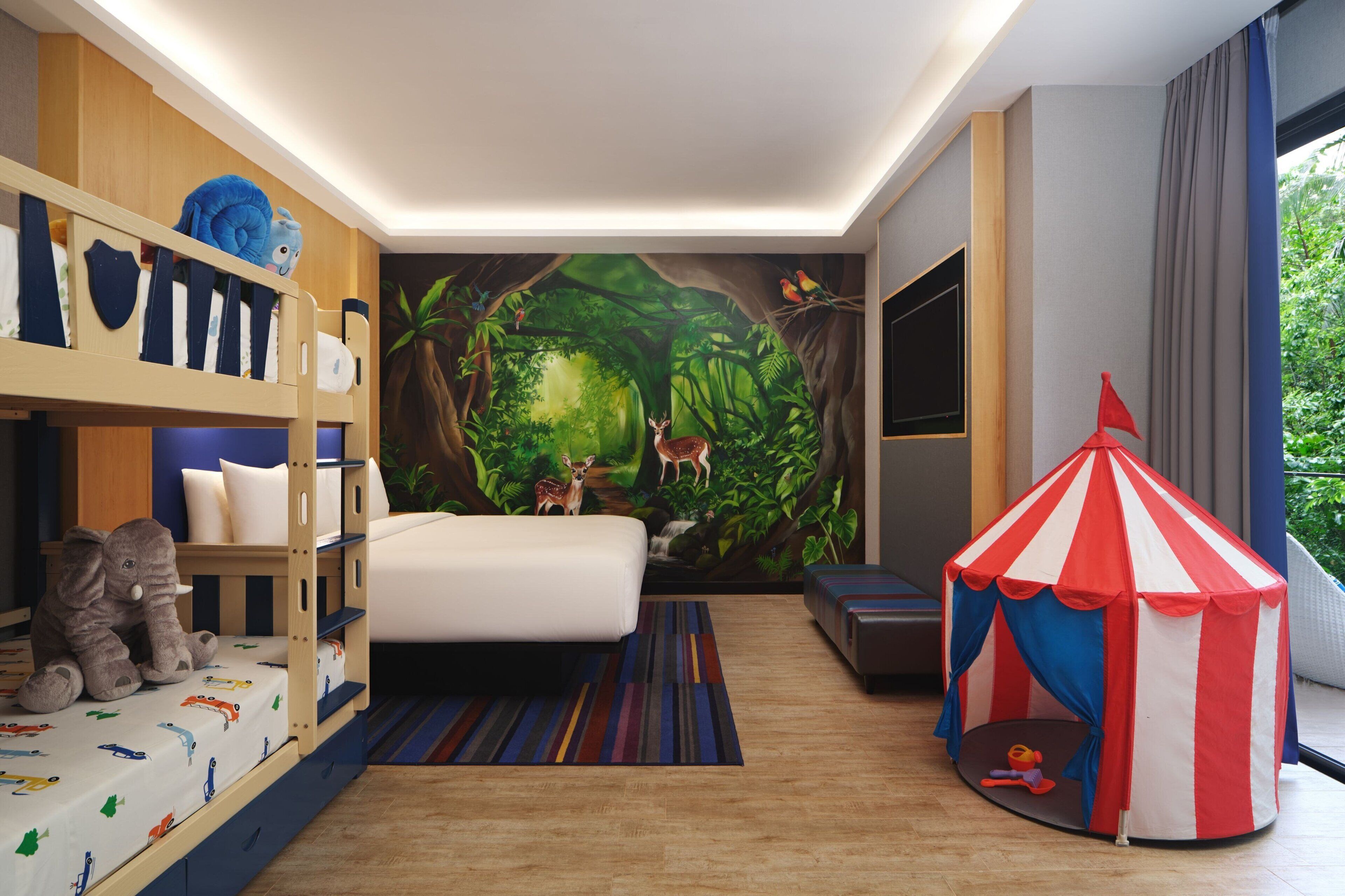 A child-friendly room with bunk beds, a tent, and a forest mural.
