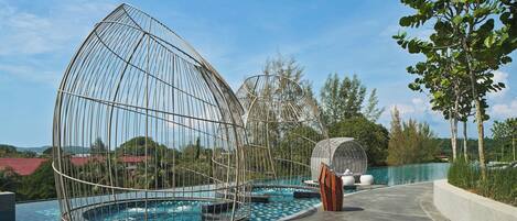 Una piscina con una estructura de entramado metálico singular, rodeada de un diseño de baldosas de rombos.