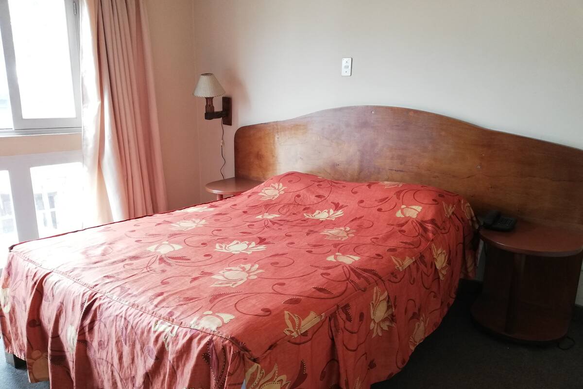 A room with a bed, a nightstand, a lamp, and a telephone.