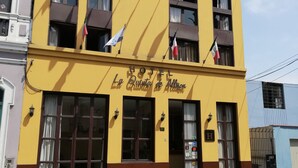 A hotel with multiple flags, a yellow facade, and a sign reading "HOTEL La Quinta de Altizon". - La Quinta de Allison Hotel & Backpackers (Lima)
