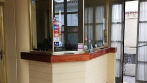 A reception desk with a glass partition, a tiled floor, and a door leading outside. - La Quinta de Allison Hotel & Backpackers (Lima)