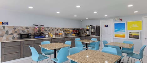 Una cocina moderna con encimeras de granito, sillas azules y un microondas.