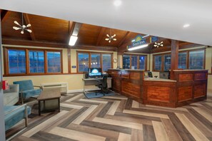 A reception area with wooden paneling, a reception desk, a computer, and seating. - Days Inn by Wyndham Knoxville North (Knoxville)