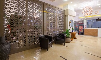 Vestíbulo con mostrador de recepción, zona de estar, paneles decorativos y un reloj.
