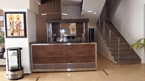 Taulell de recepció amb una màquina de cafè, un safataire i una escala.