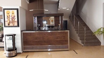 Un mostrador de recepción con una máquina de café, un cubo de basura y una escalera.