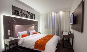 Una habitación de hotel con una cama grande, un escritorio, una silla, un televisor y un teléfono.