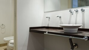 Ein Badezimmer mit einem weißen Waschbecken, einem Spiegel und einer Toilette.