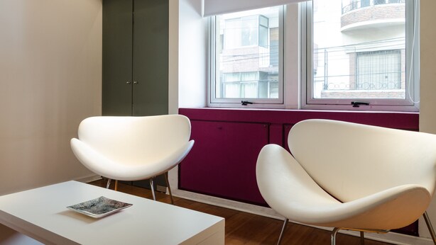 Ein modernes Zimmer mit zwei weißen Stühlen, einem weißen Tisch und einem violetten Schrank.