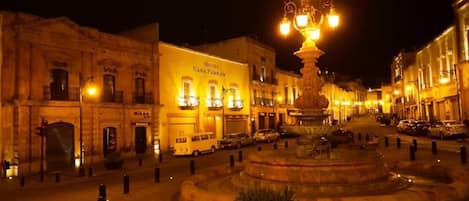 Edificio histórico con una fuente en el centro, rodeado por una plaza circular con pilares.