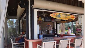 Un espace bar avec un comptoir, des tabourets de bar et une enseigne indiquant « Land Shark Lager ».