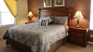 Un dormitorio con una cama grande, dos lámparas de noche, una mesita de noche y dos cuadros en la pared.