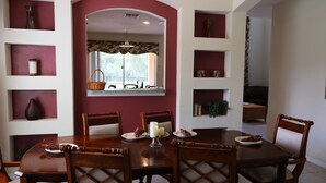 Comedor con mesa y sillas de madera, rodeado de estanterías con adornos.