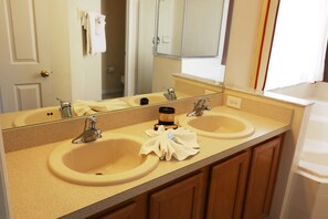 A bathroom with two sinks, a large mirror, and wooden cabinets. - 7BR 4.5BA Home in Emerald Island Resort by CV-2708 (Kissimmee)