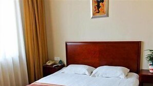A hotel room with a wooden bed, white bedding, a bedside table with a lamp, and a painting on the wall. - Greentree Inn Wuxi Guangrui Road Hotel (Wuxi)