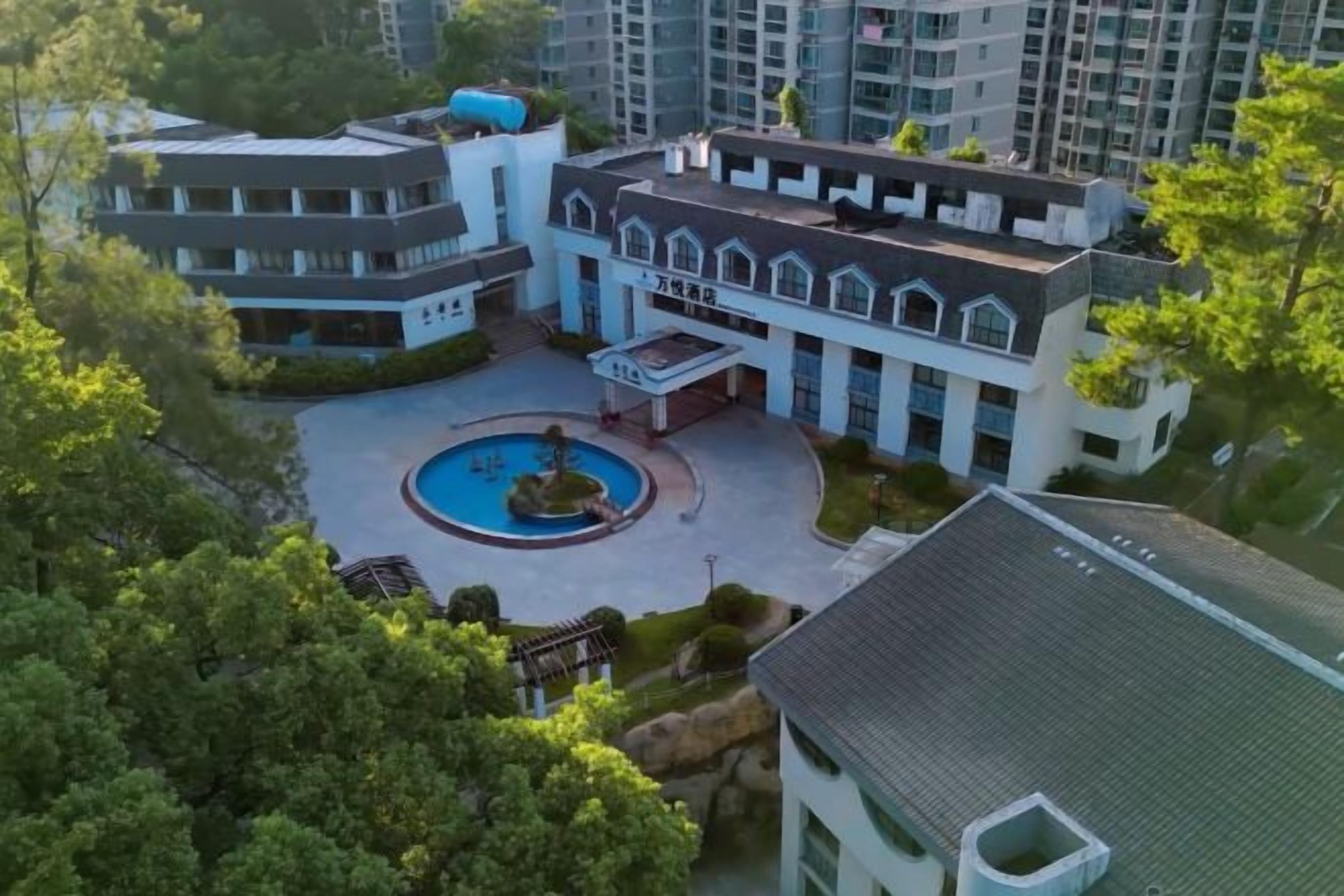 A multi-story residential building with a central courtyard, a swimming pool, and a small bridge.