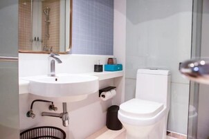 Un baño moderno con un lavabo blanco, un inodoro y una zona de ducha.