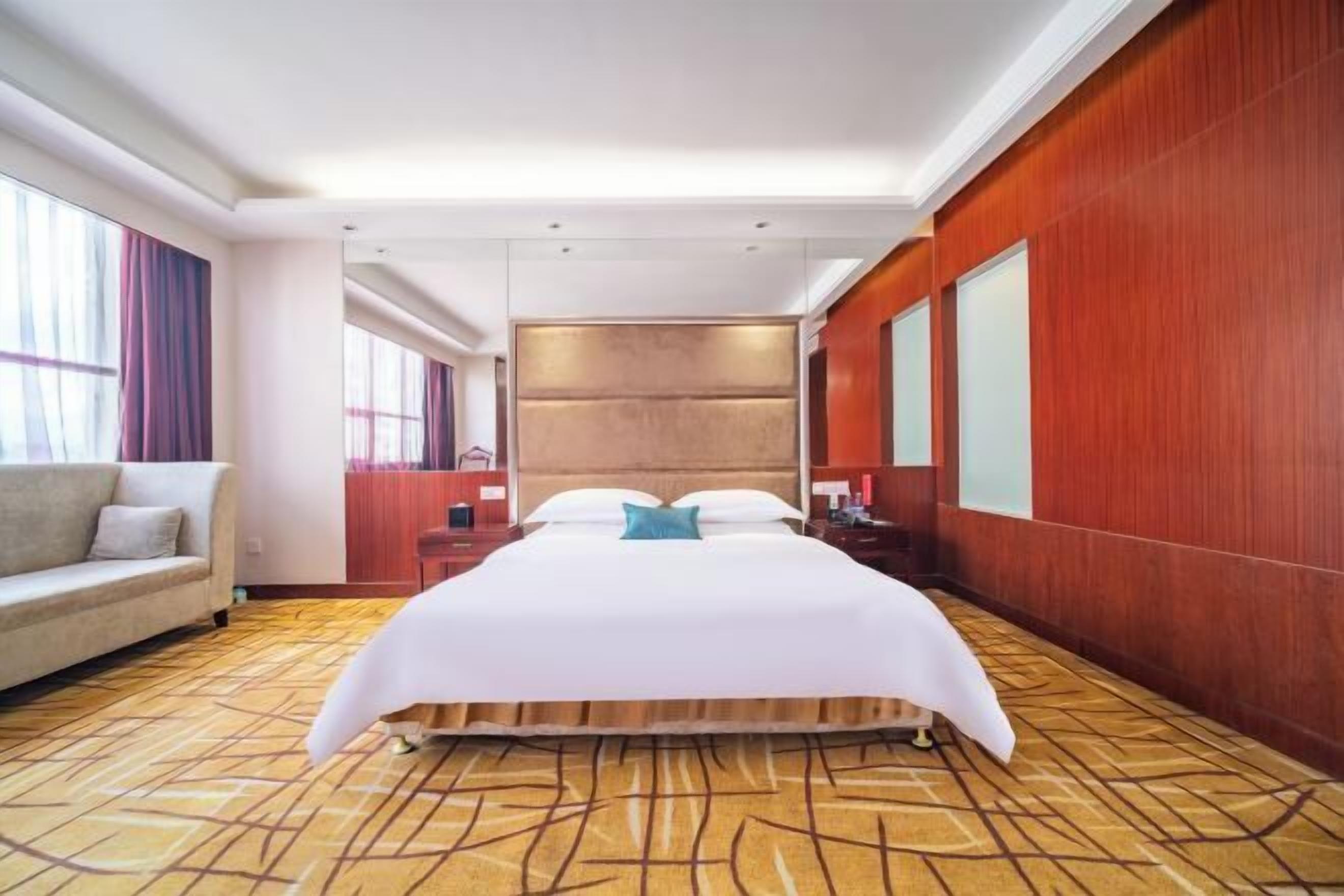 Ein Hotelzimmer mit einem großen Bett, einer Schlafcouch, einer Holzvertäfelung und einem gemusterten Teppich.