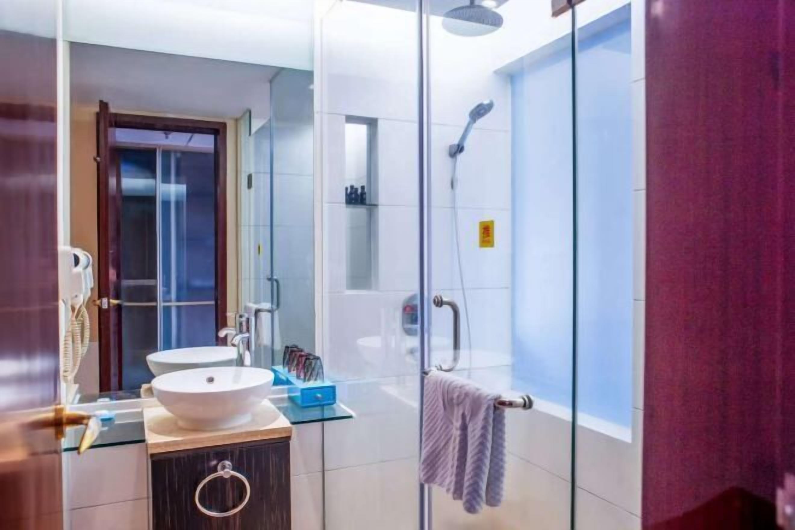 Une salle de bain moderne avec une douche à parois de verre, un lavabo blanc et un meuble-lavabo avec un plateau en verre.