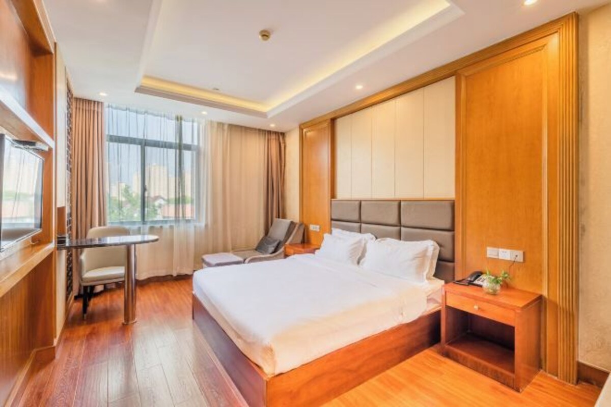 A hotel room with a large bed, a desk, and a chair.