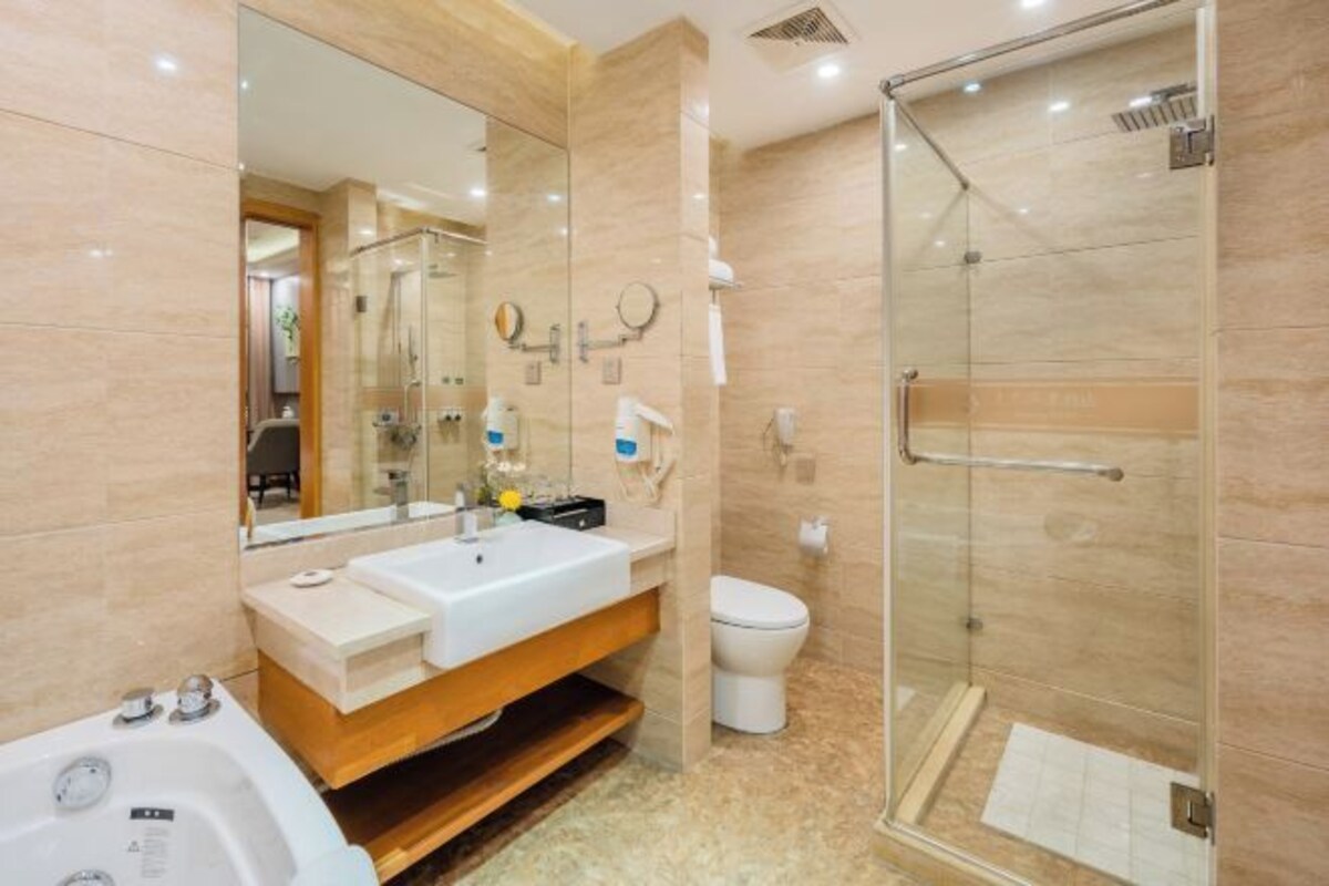 A modern bathroom with a glass-enclosed shower, a white sink, and a toilet.