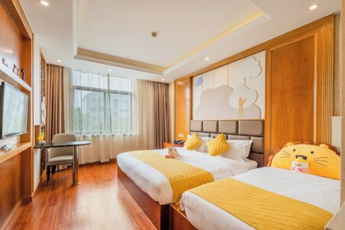 A hotel room with two beds, a desk, and a TV.