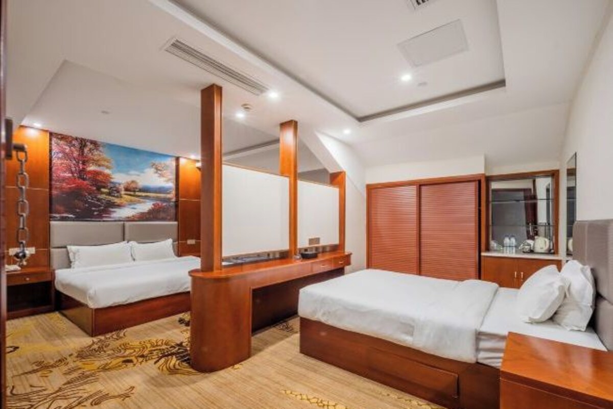 A hotel room with two beds, a large painting, wooden furniture, and a mirror.