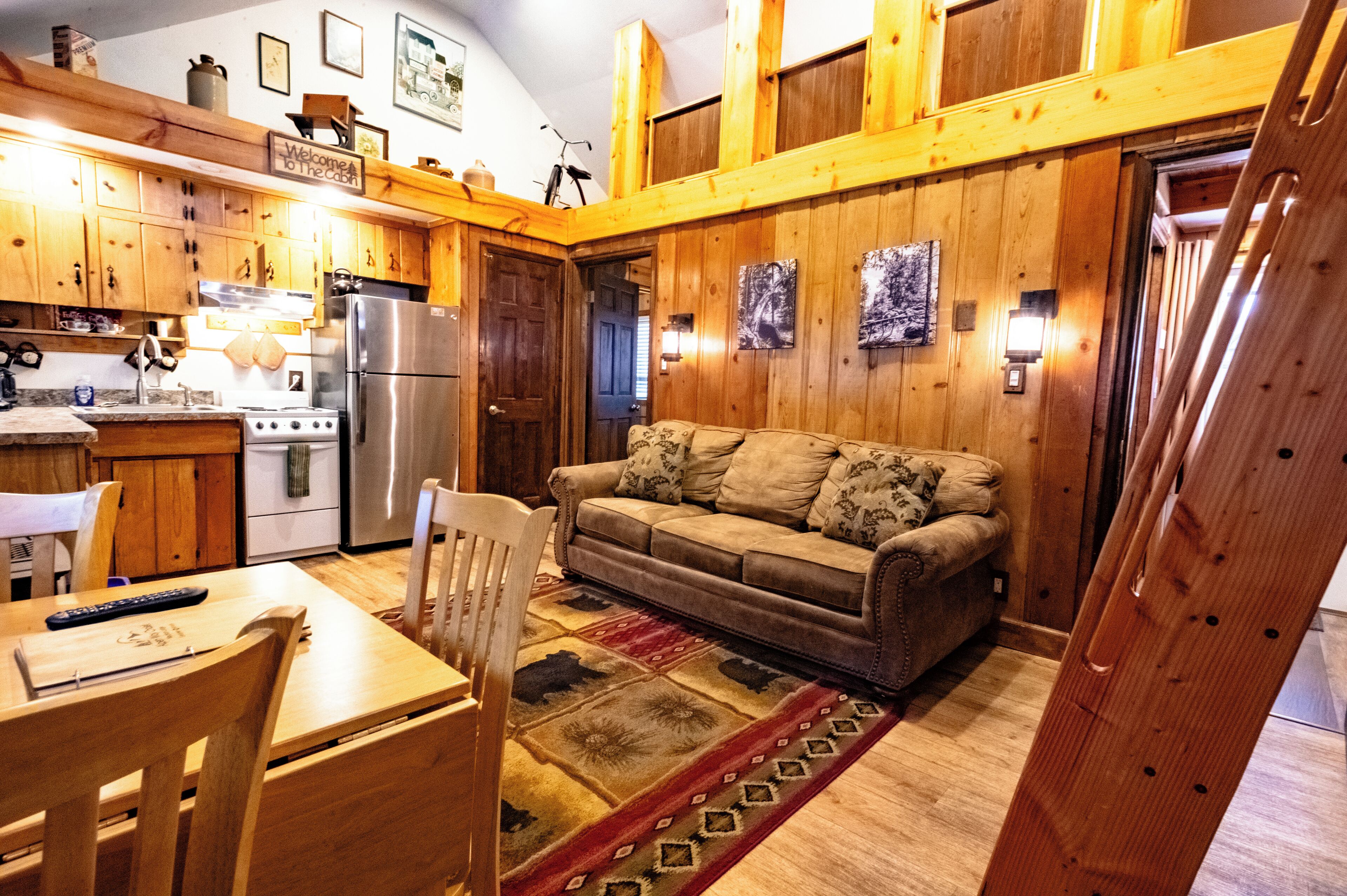 A cozy kitchen with wooden cabinets, a refrigerator, and a dining area with a table and chairs.