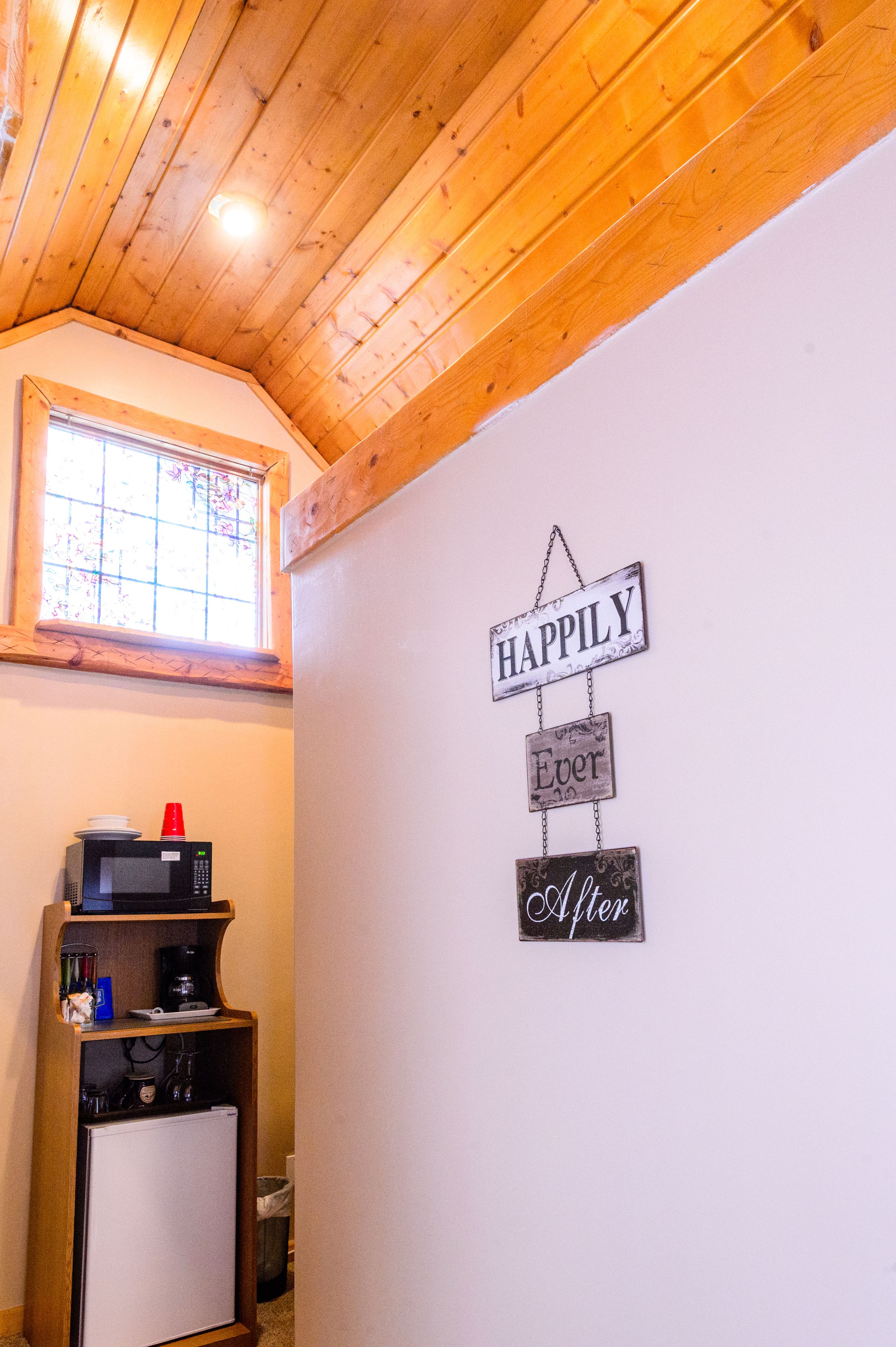 A kitchen with wooden ceiling, a microwave, a coffee maker, and a refrigerator.