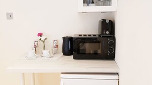 A compact kitchenette with a microwave, toaster, and small refrigerator. - The 329 (Enfield)