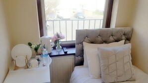 A bedroom with a bed, bedside table, and a window with a view of the street. - The 329 (Enfield)