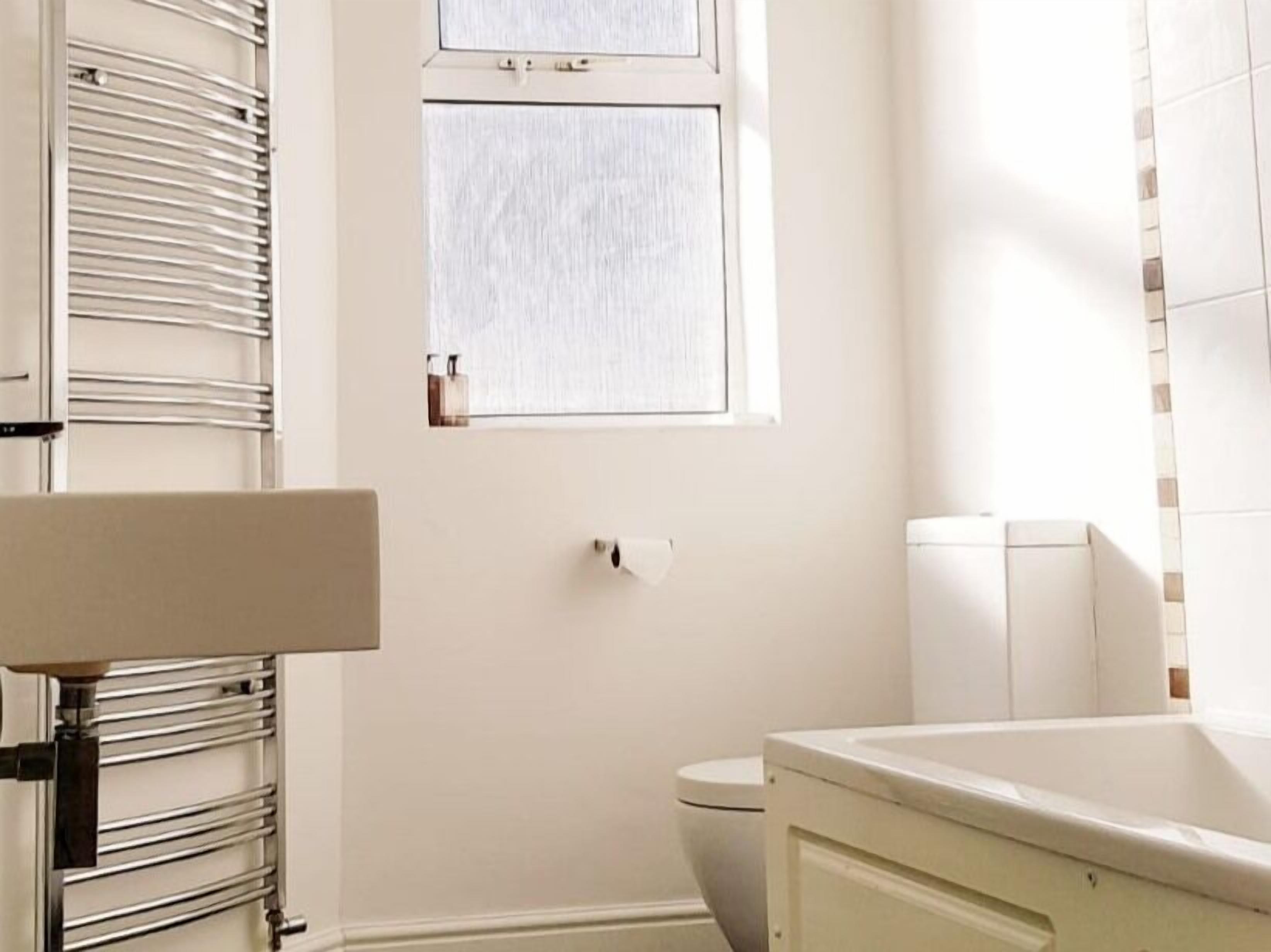 Une salle de bain avec des toilettes, une fenêtre et un porte-serviettes.